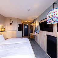 Blick in ein Hotelzimmer des Hotels "Bretterbude" auf Büsum mit Wandleuchte im Surfhosen-Design